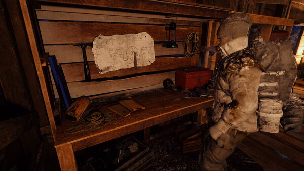 A screenshot from Permafrost showing a character in snowy gear examining a workbench with tools and a map in a wooden cabin.
