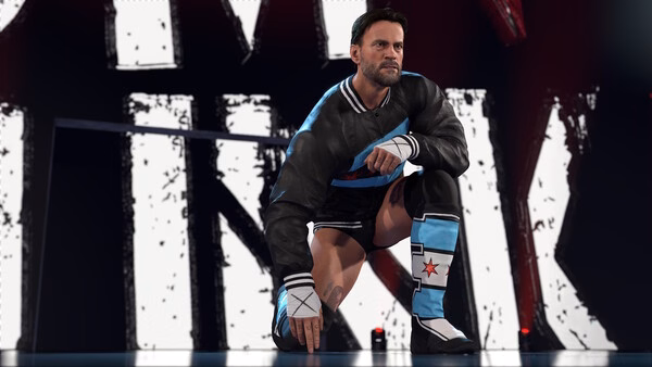Screenshot from WWE 2K26 showing a wrestler in a black jacket and blue boots, kneeling in front of a large graphic background.