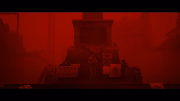 Screenshot from SILENT HILL: Townfall showing a red-tinted scene with a figure near a monument surrounded by protest signs.
